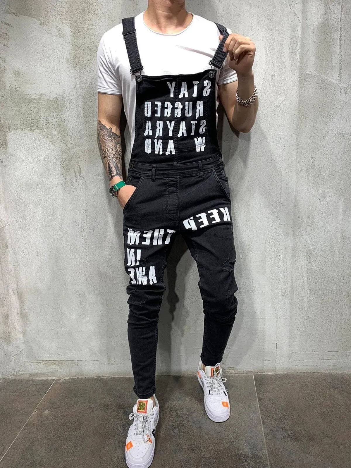 Men's black braces ripped jeans jumpsuit with adjustable shoulder straps on a model