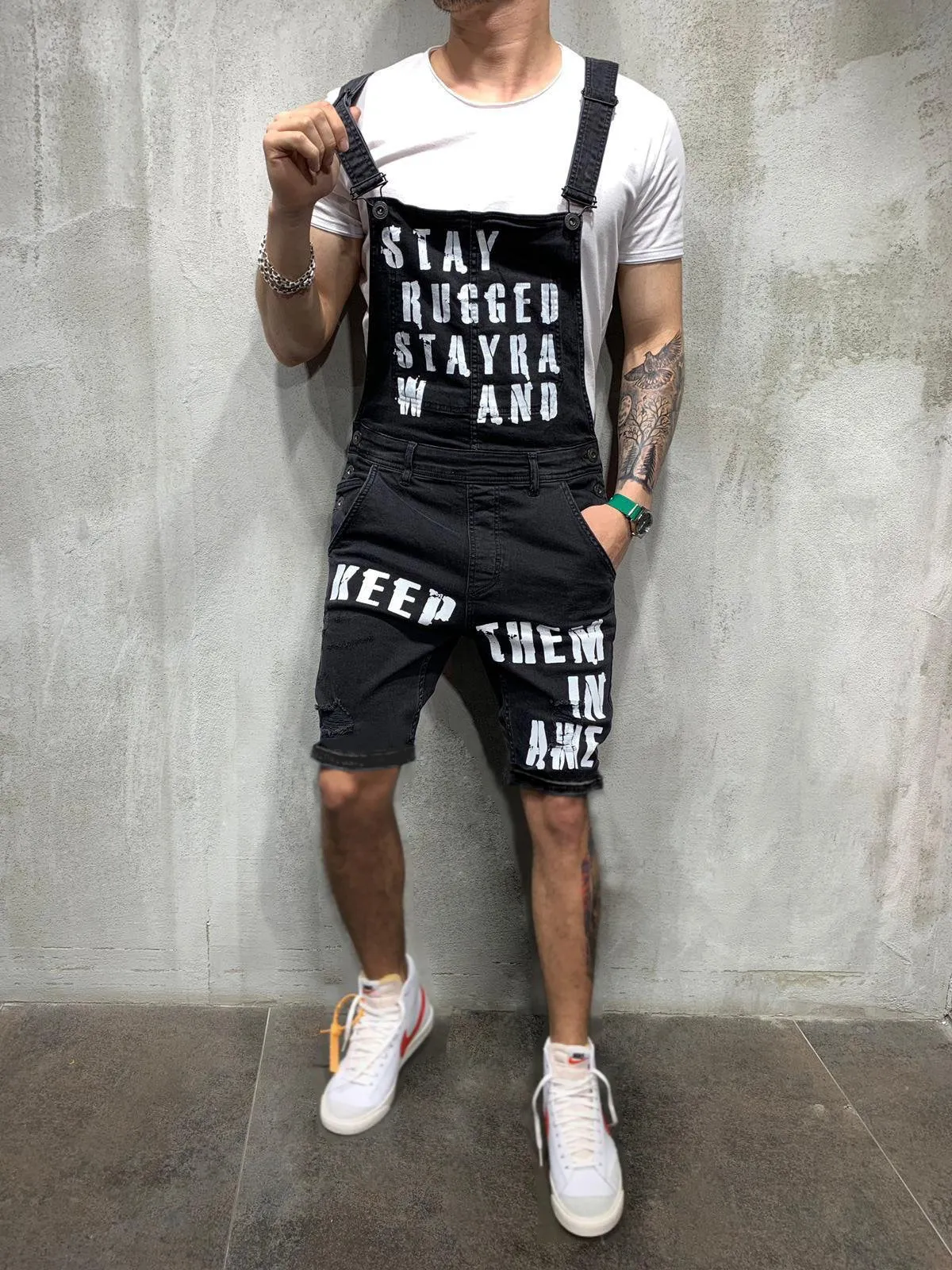 Men's black braces ripped jeans jumpsuit with adjustable shoulder straps on a model