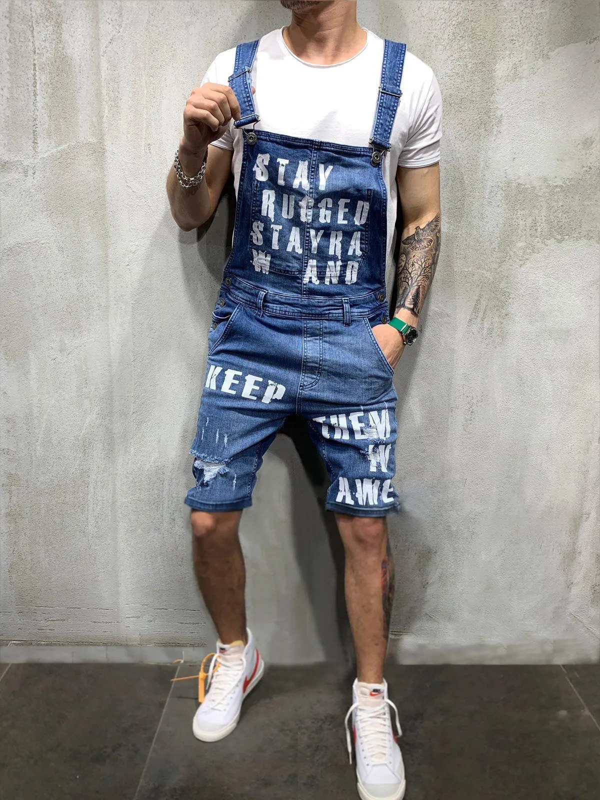Men's black braces ripped jeans jumpsuit with adjustable shoulder straps on a model