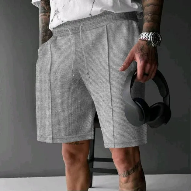 Solid colour five-point polyester sports shorts in khaki with elastic waistband, side view on model