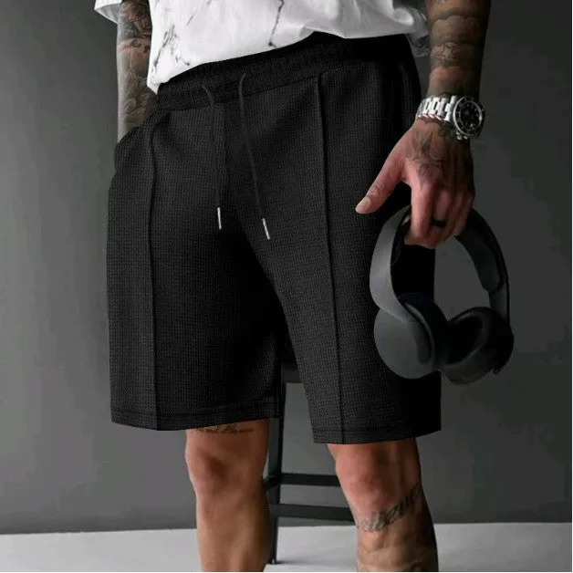 Solid colour five-point polyester sports shorts in khaki with elastic waistband, side view on model