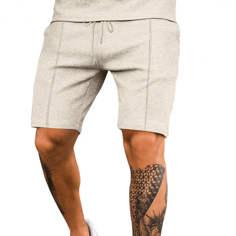 Solid colour five-point polyester sports shorts in khaki with elastic waistband, side view on model