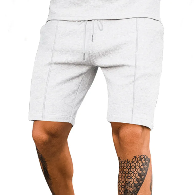 Solid colour five-point polyester sports shorts in khaki with elastic waistband, side view on model