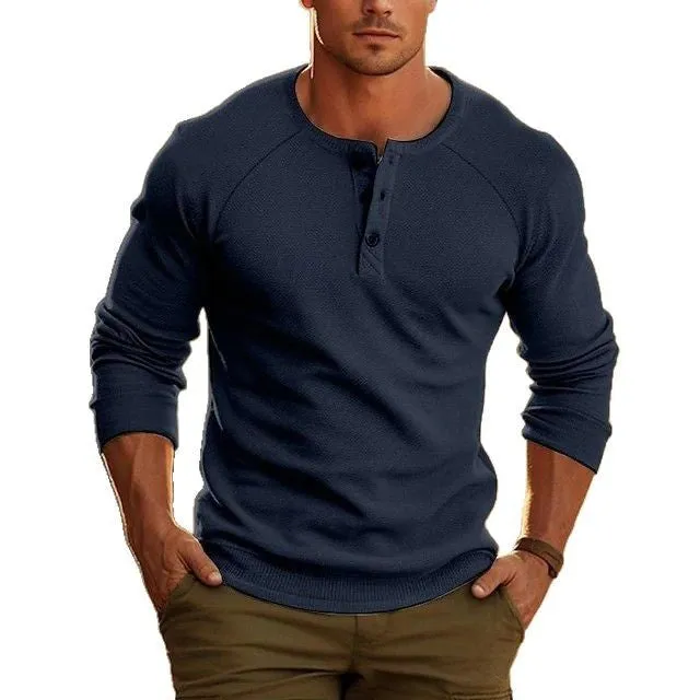 Man wearing a navy blue long-sleeved T-shirt with a Henry collar, made from cotton blend fabric.