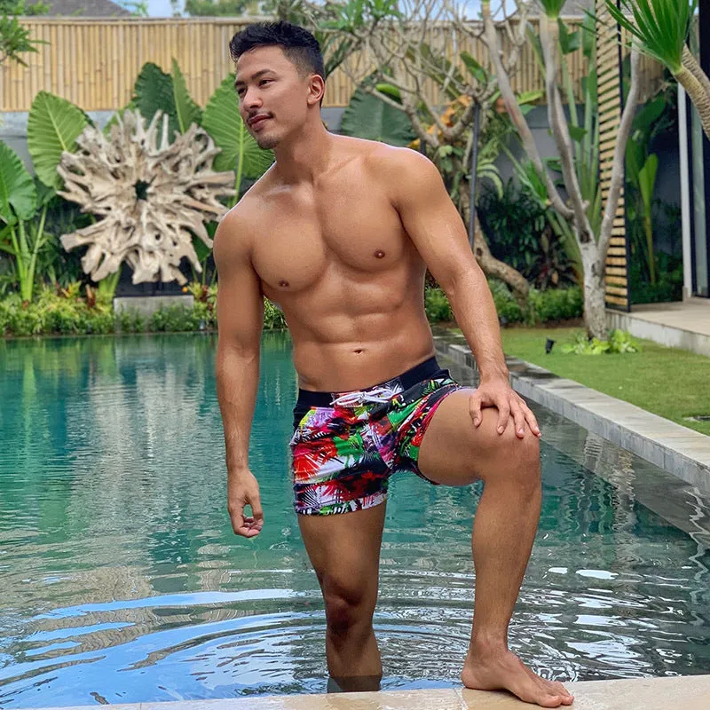 Men's spandex polyester swim shorts with elastic waist and drawstring on a beach background