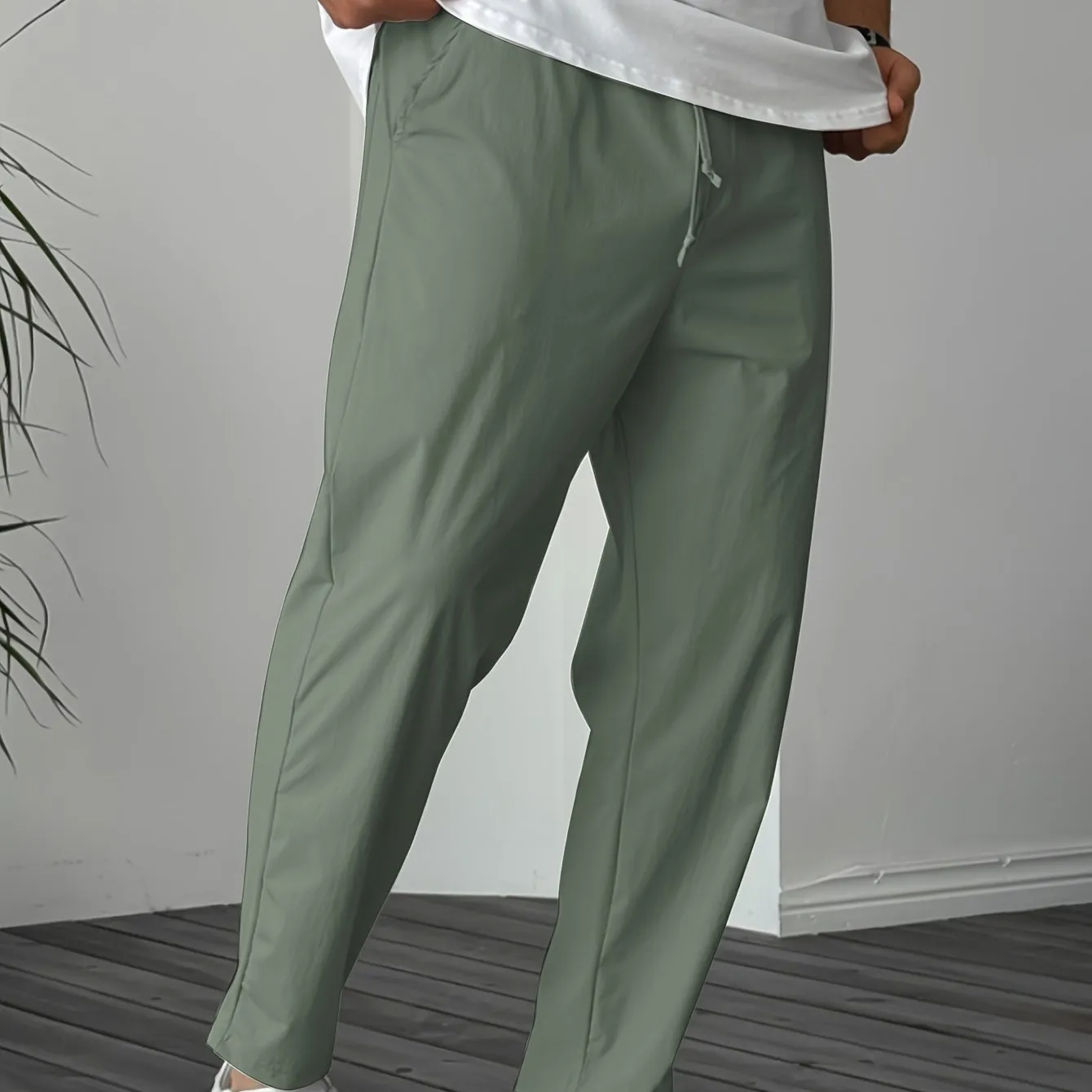 Man wearing khaki straight-leg drawstring trousers with a tonal ribbon pocket detail.