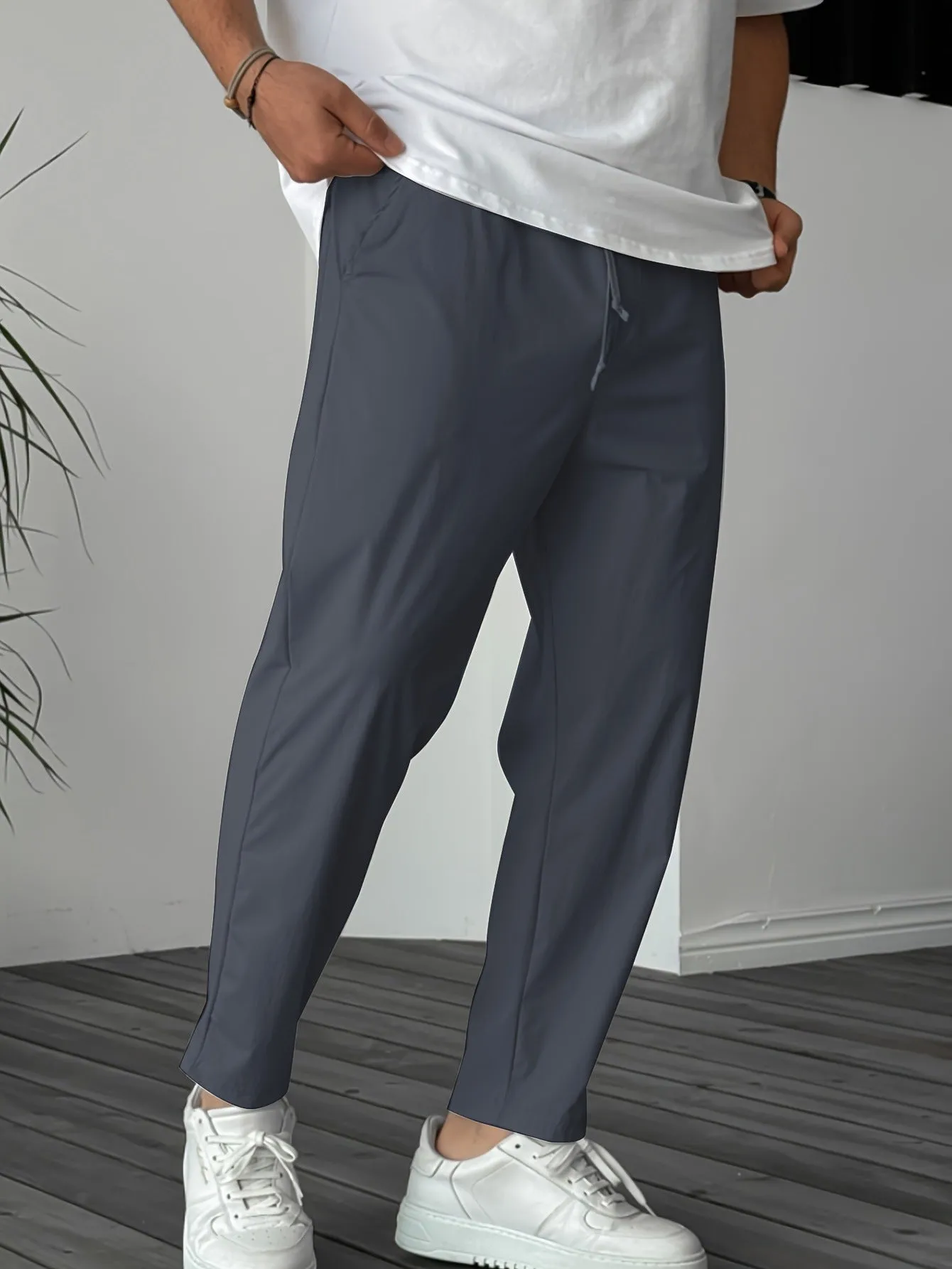 Man wearing khaki straight-leg drawstring trousers with a tonal ribbon pocket detail.