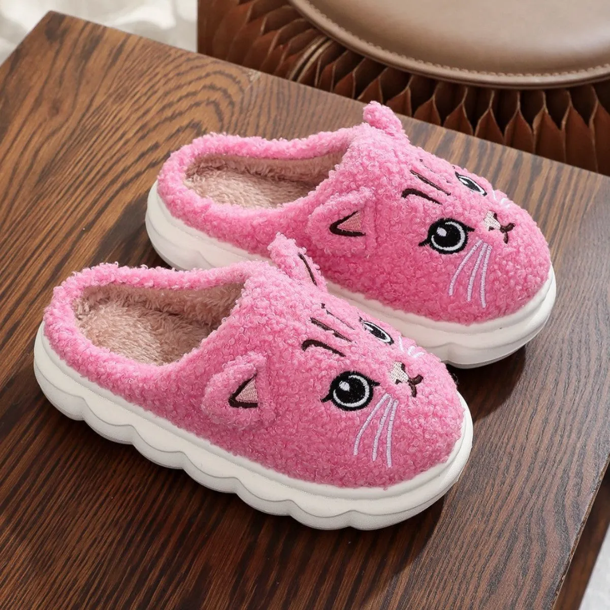 Pair of pink winter cartoon cat fluffy slippers on floor, non-slip EVA sole