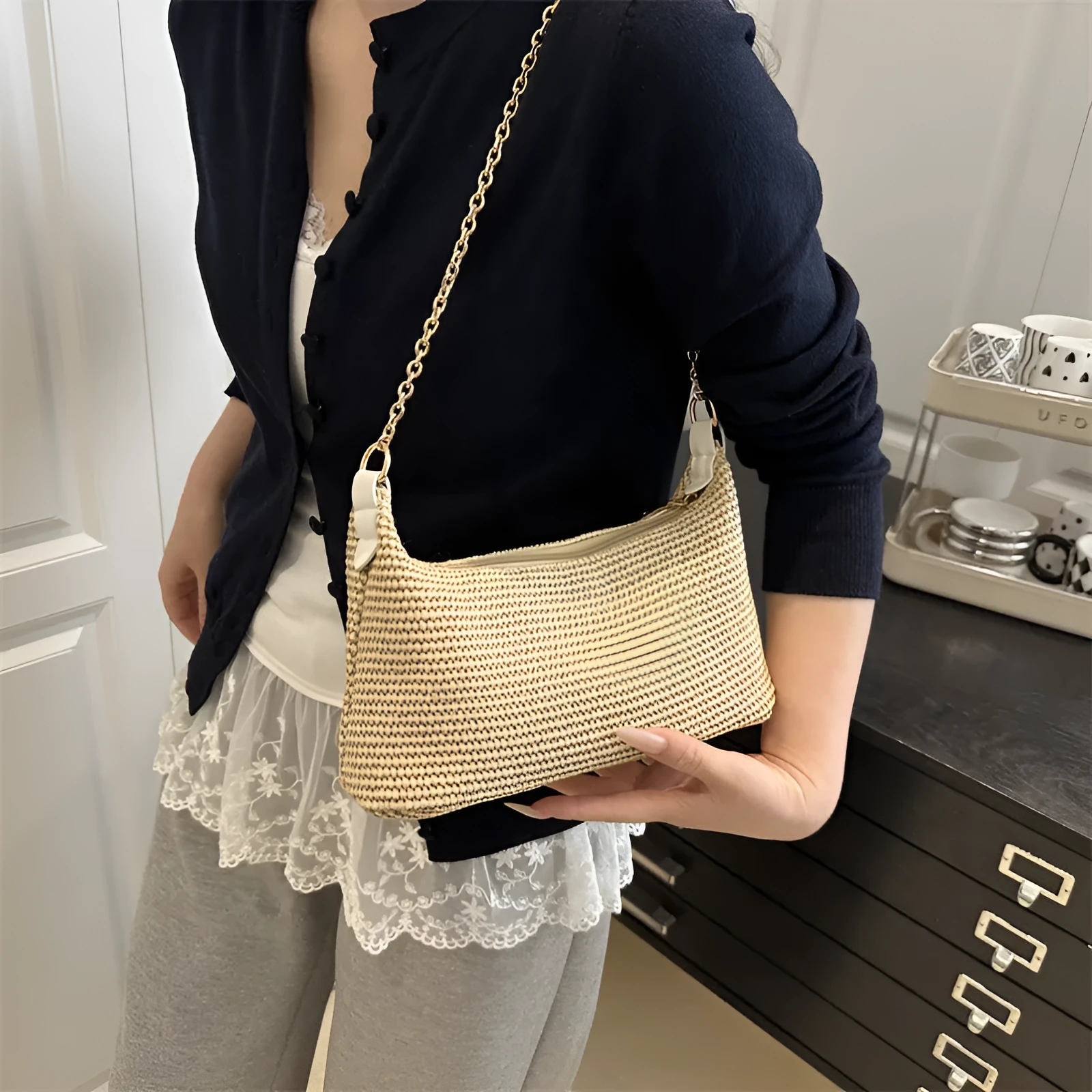 Khaki woven straw crossbody handbag with square shape and crossbody strap.
