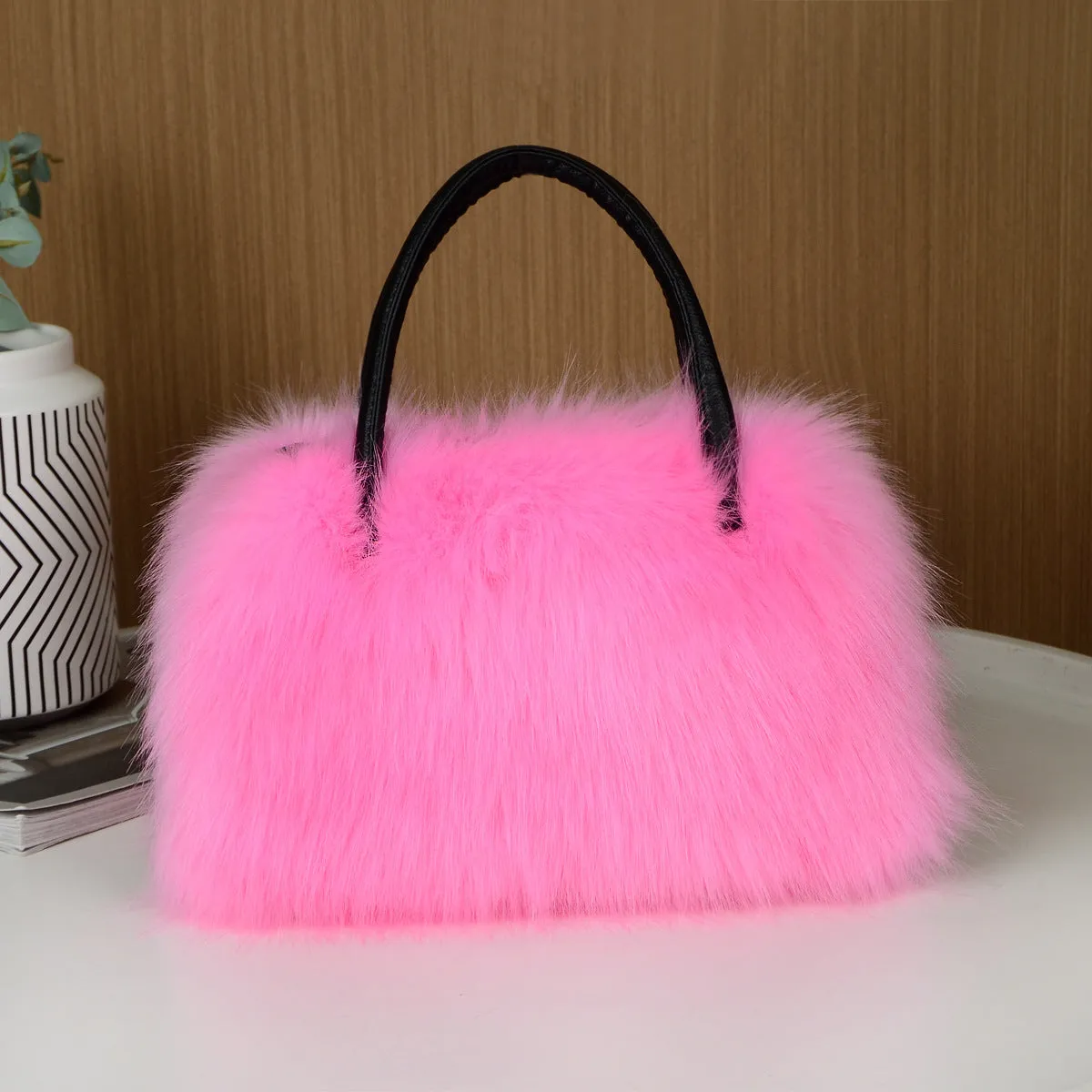 Hand-carrying square plush bag in pink with soft faux fur exterior and horizontal shape