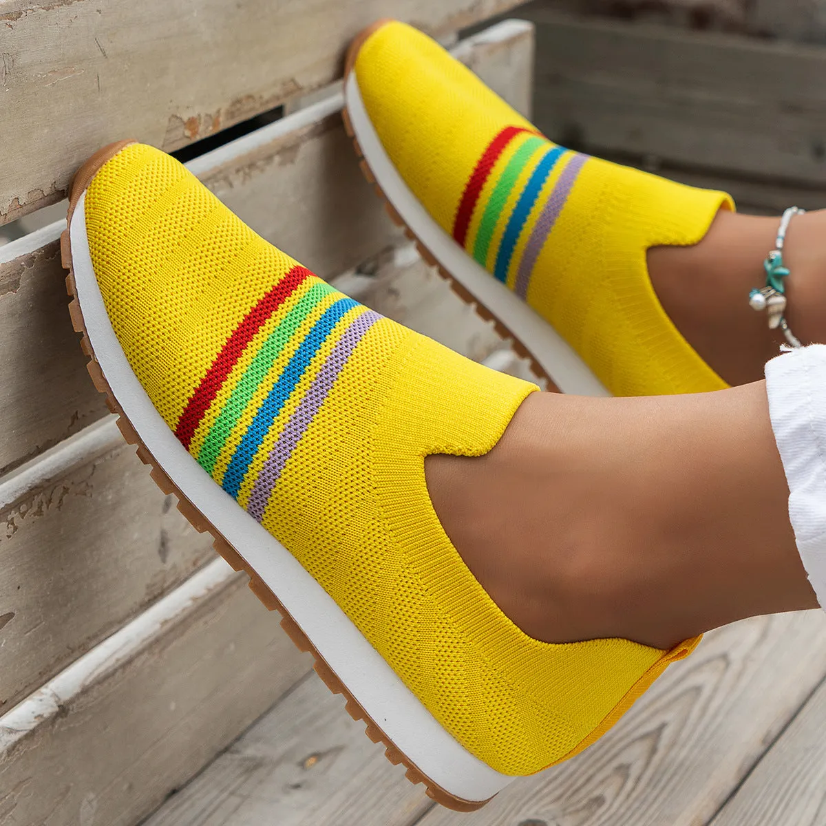 Women's casual flat sneaker pumps in beige with low wedge heel and round toe, side view on wooden floor