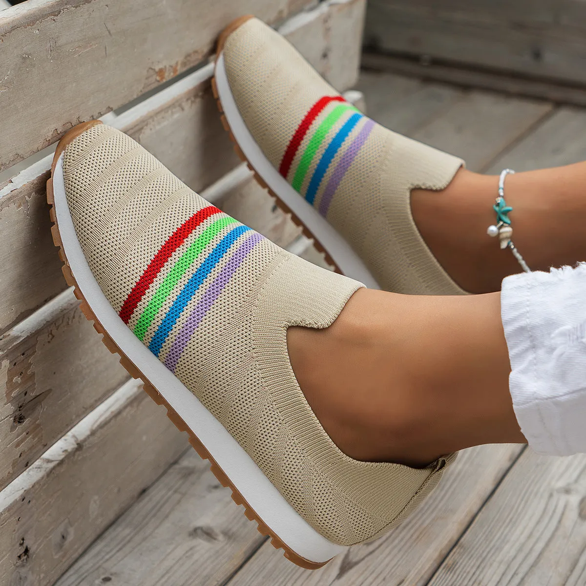 Women's casual flat sneaker pumps in beige with low wedge heel and round toe, side view on wooden floor