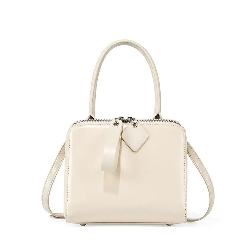 Open grain leather handbag in black with visible grain texture and welt pocket on front