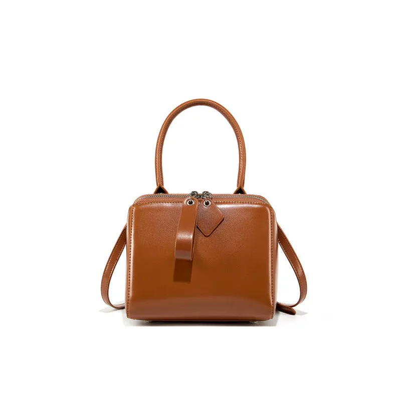 Open grain leather handbag in black with visible grain texture and welt pocket on front