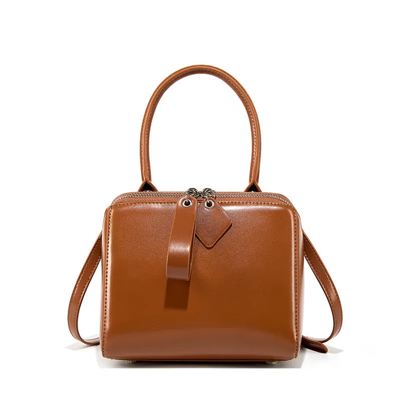 Open grain leather handbag in black with visible grain texture and welt pocket on front