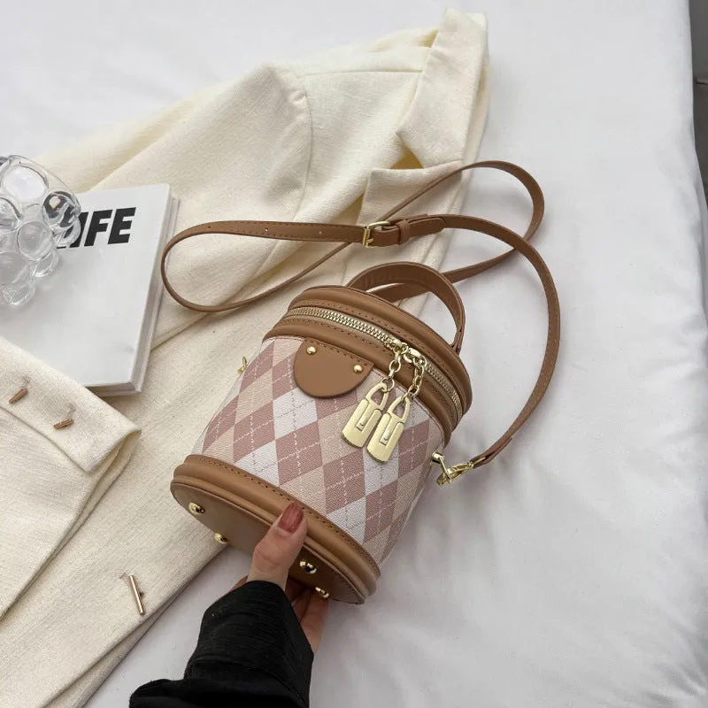Textured rhombus cylindrical PU bucket bag in beige with white rabbit pendant, 14 cm wide.