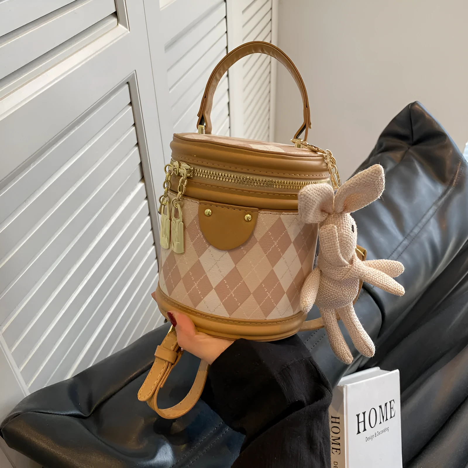 Textured rhombus cylindrical PU bucket bag in beige with white rabbit pendant, 14 cm wide.