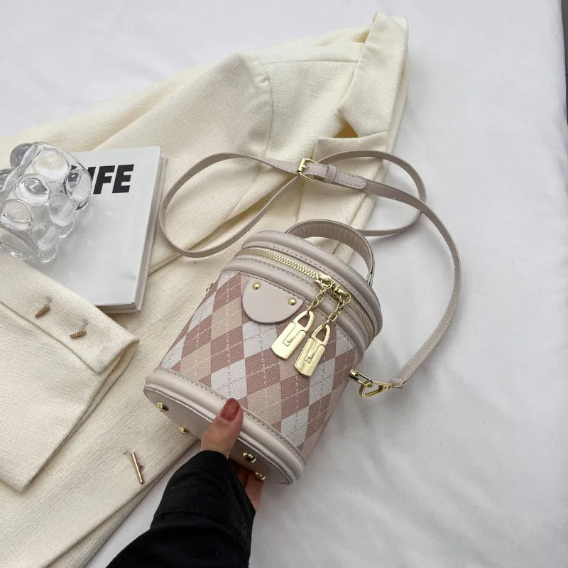 Textured rhombus cylindrical PU bucket bag in beige with white rabbit pendant, 14 cm wide.