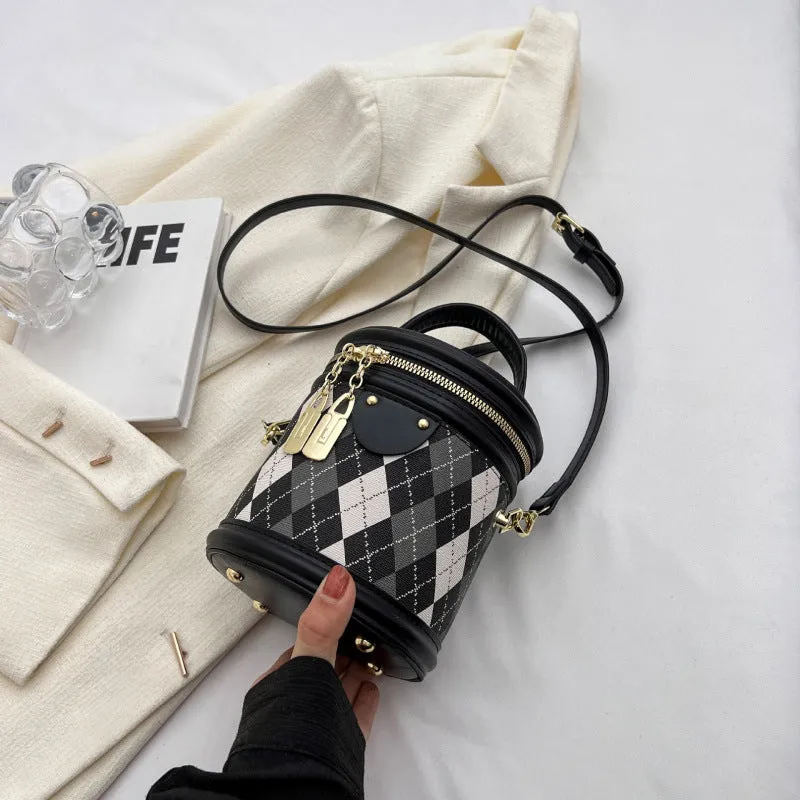 Textured rhombus cylindrical PU bucket bag in beige with white rabbit pendant, 14 cm wide.