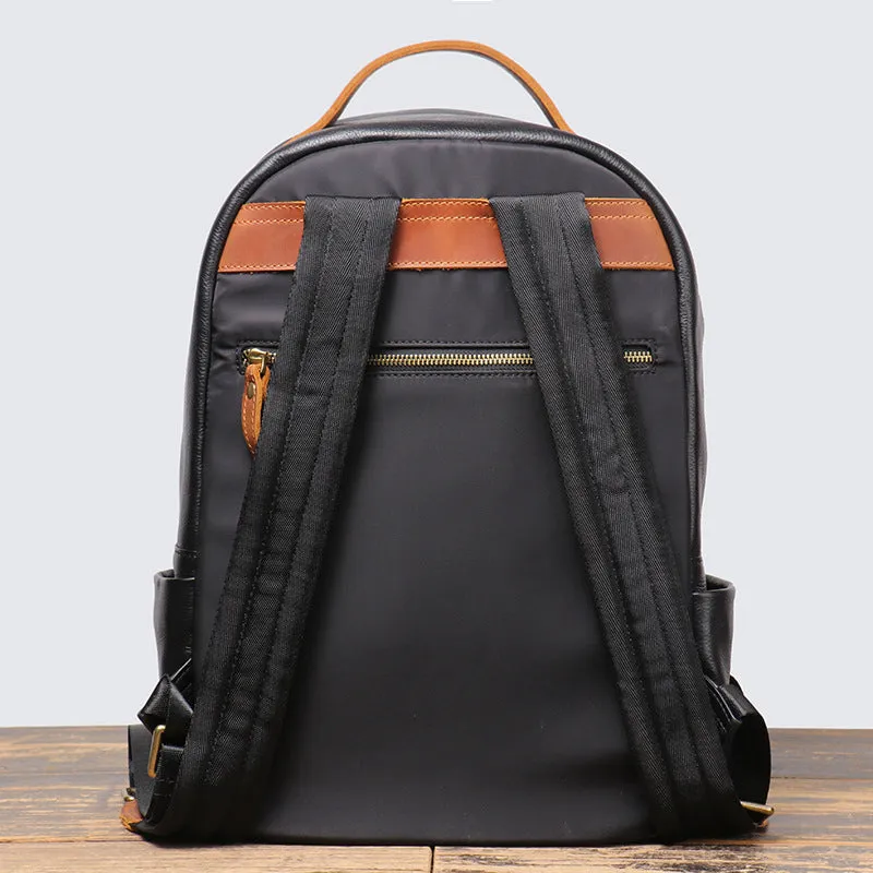 Black genuine leather expandable backpack with top grain cowhide, curved shoulder straps, and patchwork detail