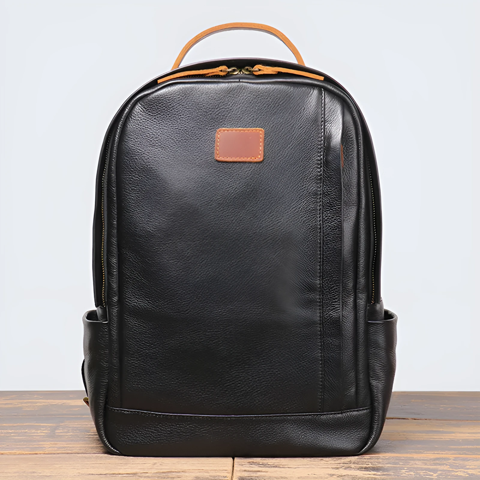 Black genuine leather expandable backpack with top grain cowhide, curved shoulder straps, and patchwork detail