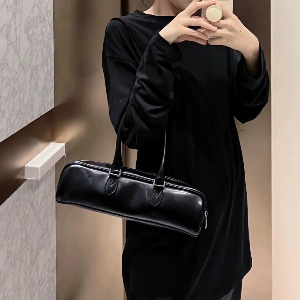 Black corduroy cowhide french stick underarm bag with sewing thread detail on a white background
