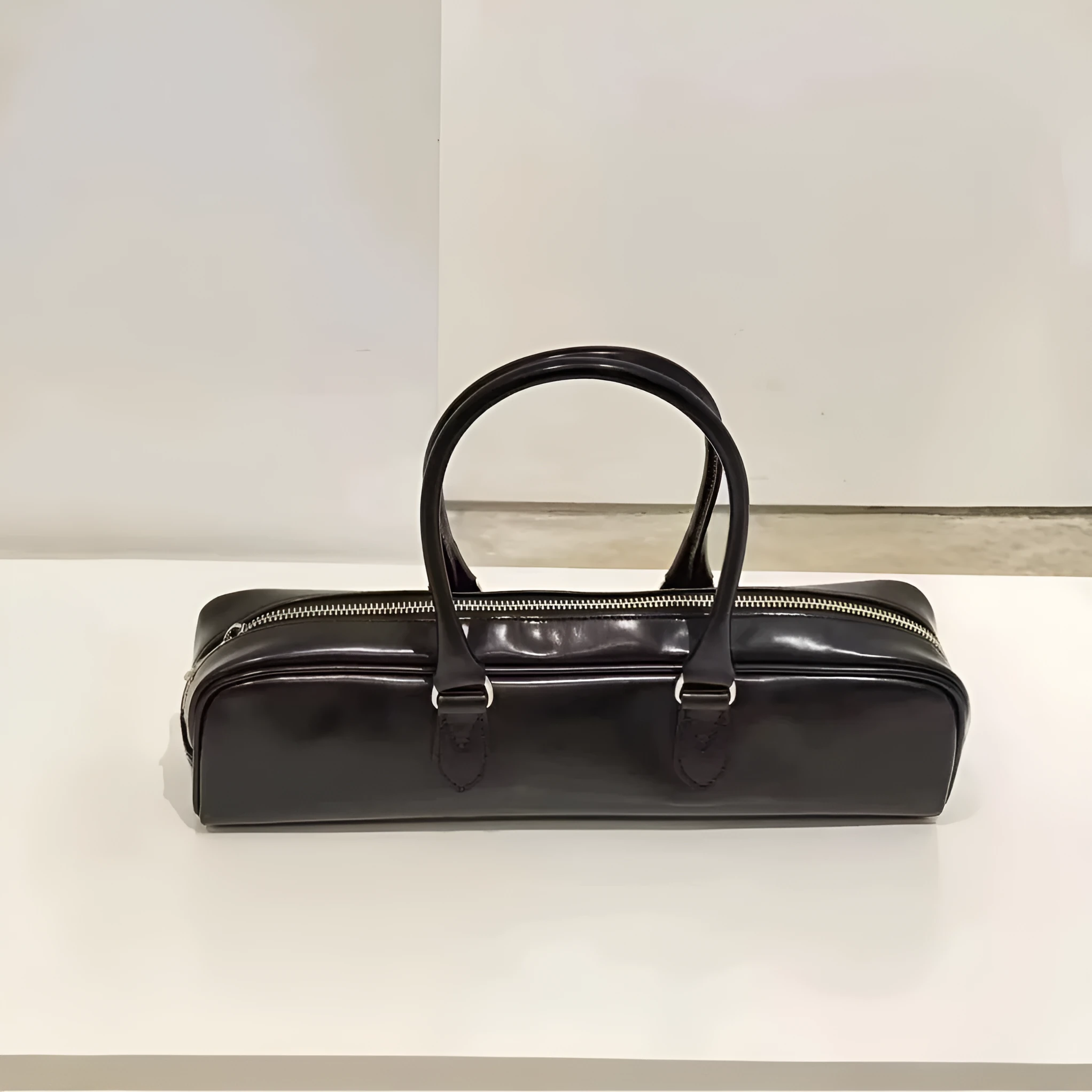 Black corduroy cowhide french stick underarm bag with sewing thread detail on a white background