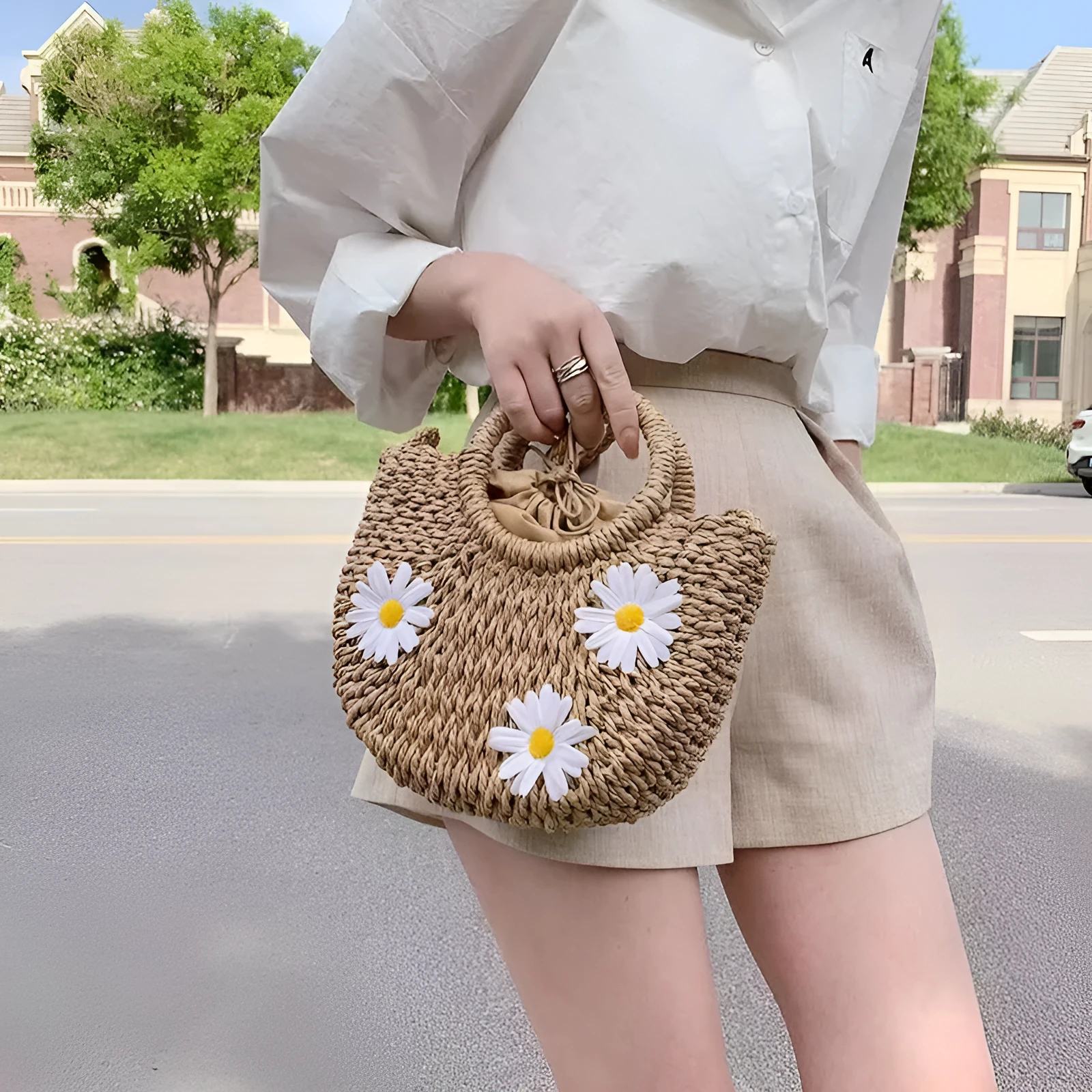 Women's light brown straw-weaved crossbody bag with daisy decoration showing woven texture