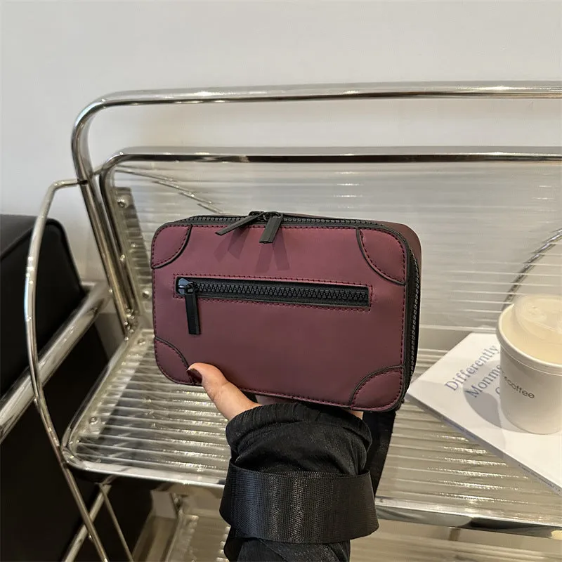 Women's black square crossbody bag showing internal mobile phone pocket and adjustable shoulder strap
