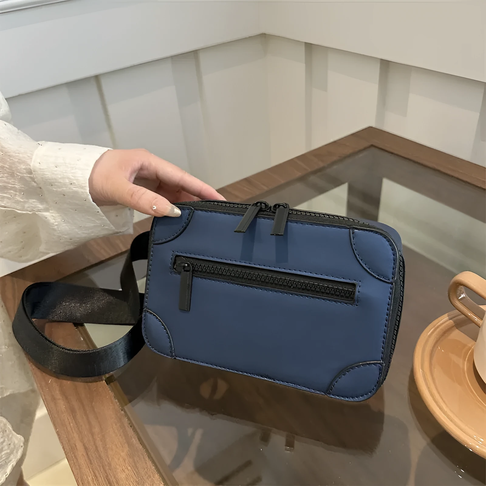 Women's black square crossbody bag showing internal mobile phone pocket and adjustable shoulder strap