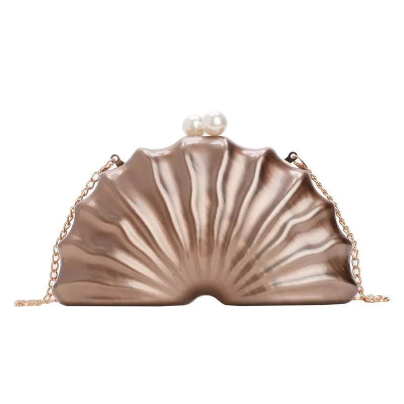 Acrylic shell-shaped clutch bag in champagne with silver chain on white background