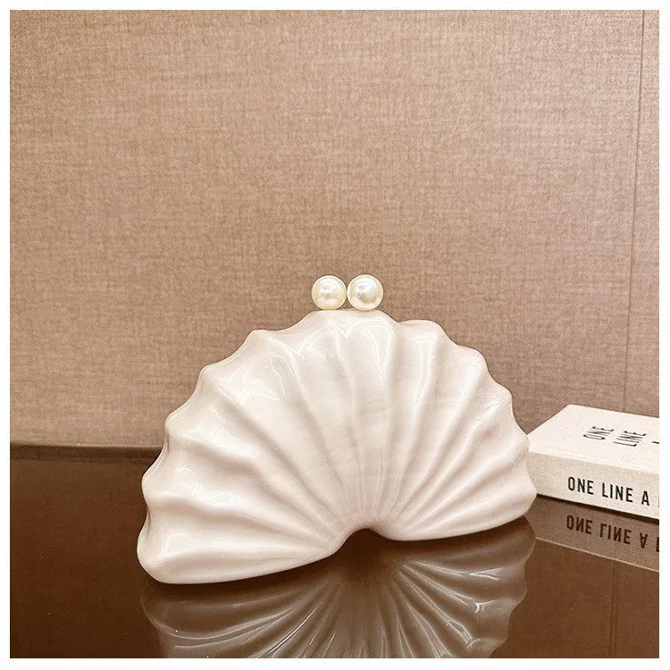 Acrylic shell-shaped clutch bag in champagne with silver chain on white background