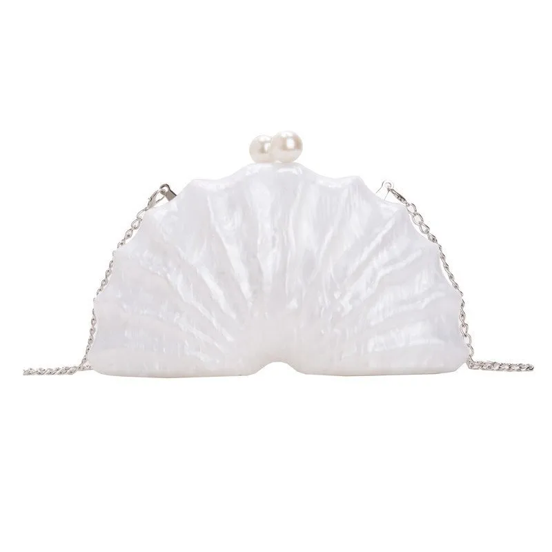 Acrylic shell-shaped clutch bag in champagne with silver chain on white background