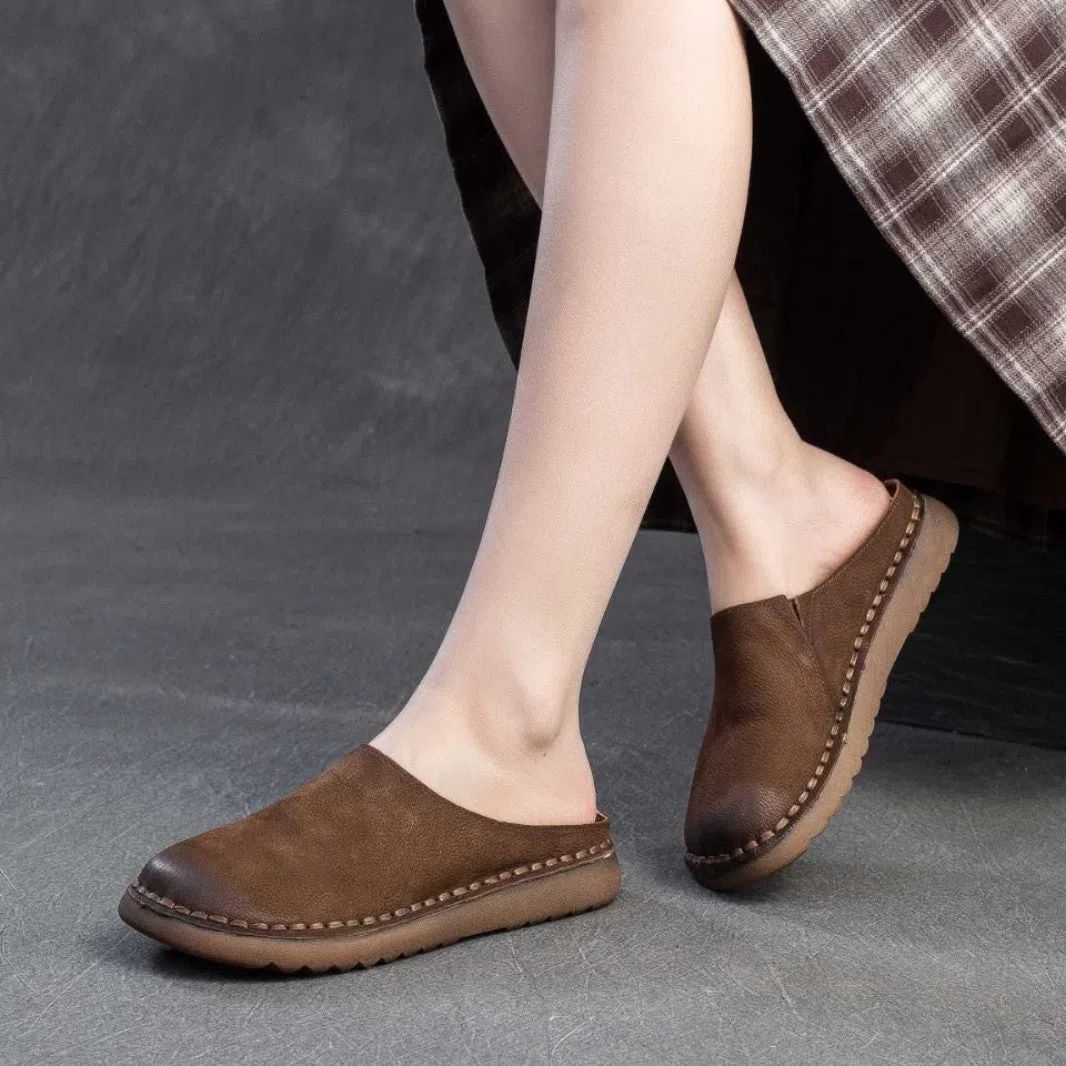 Genuine leather retro wrap-around lazy slippers in brown colour with rubber sole on a neutral background