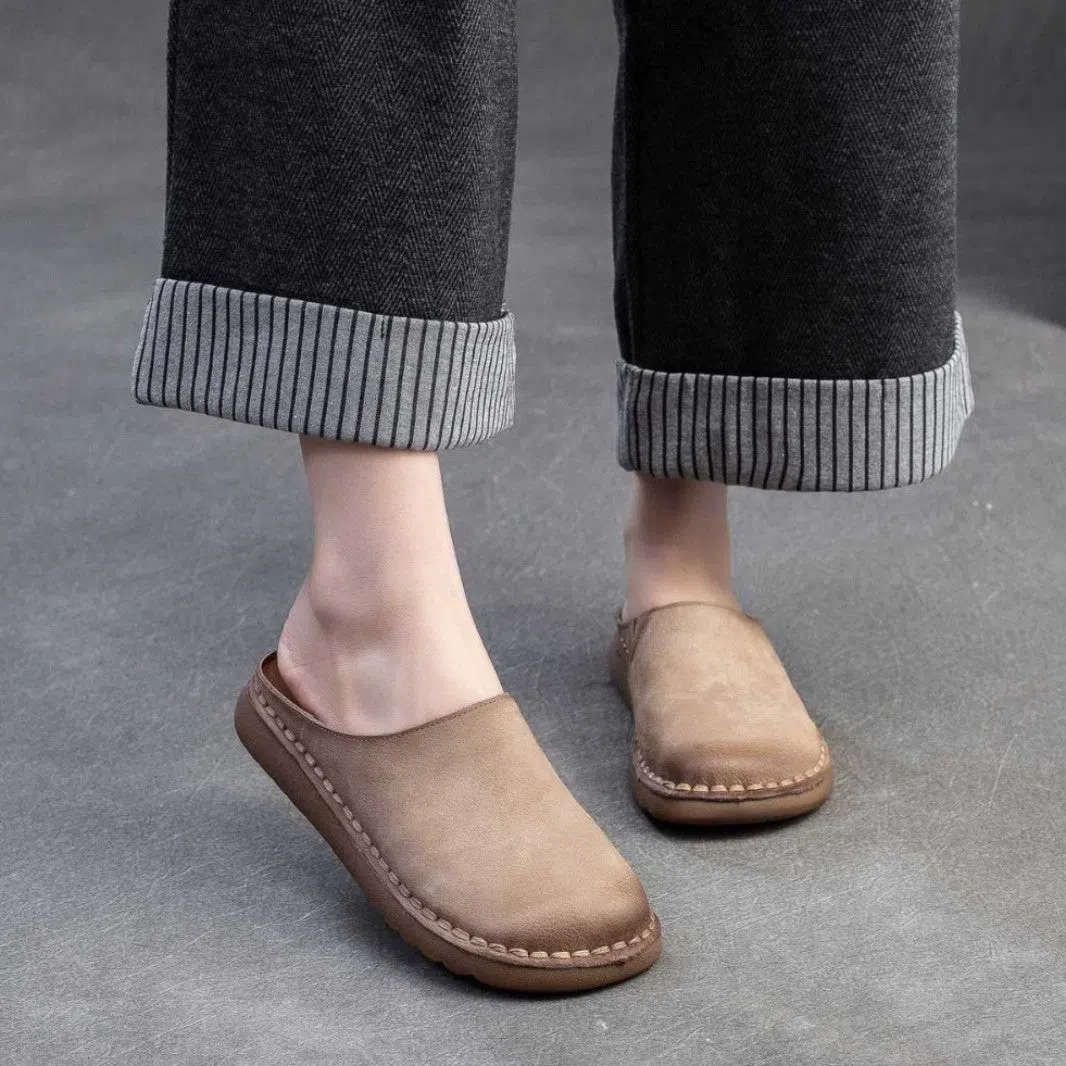 Genuine leather retro wrap-around lazy slippers in brown colour with rubber sole on a neutral background