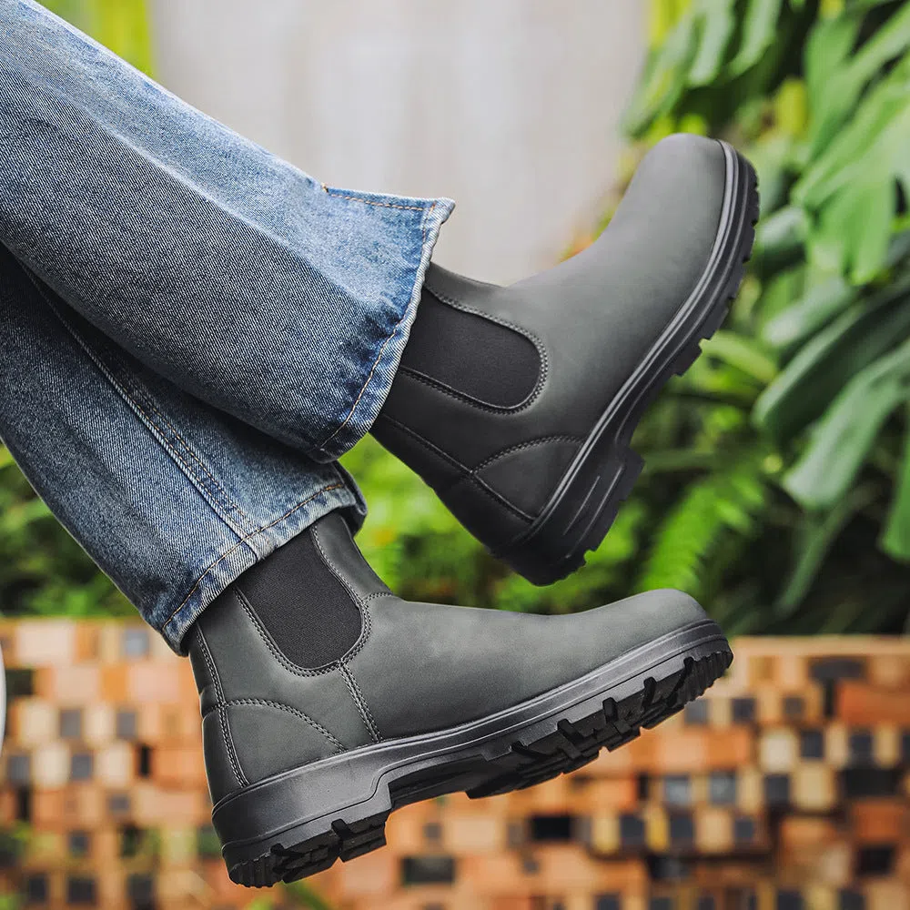 Chelsea boots in black with low wedge heel, round toe, and mid-calf shaft on a neutral background