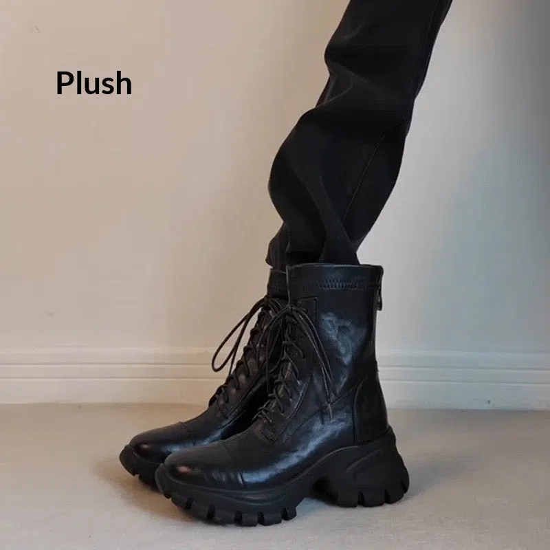 Black thick-soled motorcycle boots with back zipper and lace-up closure on a grey background