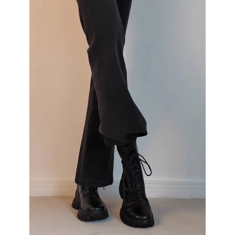 Black thick-soled motorcycle boots with back zipper and lace-up closure on a grey background