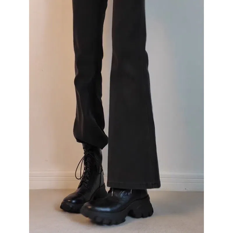 Black thick-soled motorcycle boots with back zipper and lace-up closure on a grey background