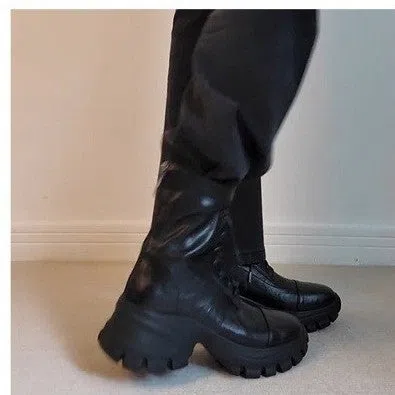 Black thick-soled motorcycle boots with back zipper and lace-up closure on a grey background