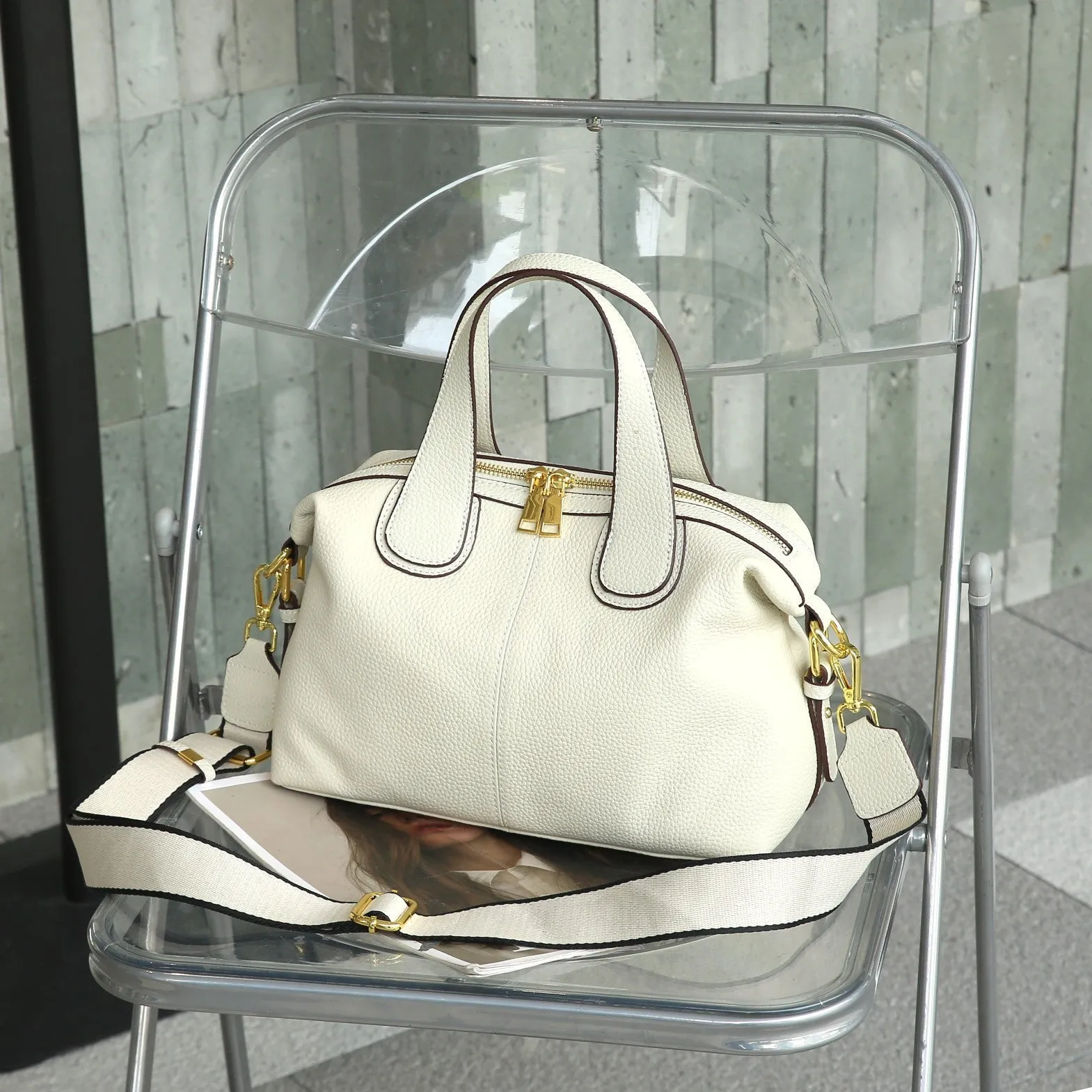 Women's leather cross-body bag in horizontal square shape with visible sewing thread detailing and interior compartments