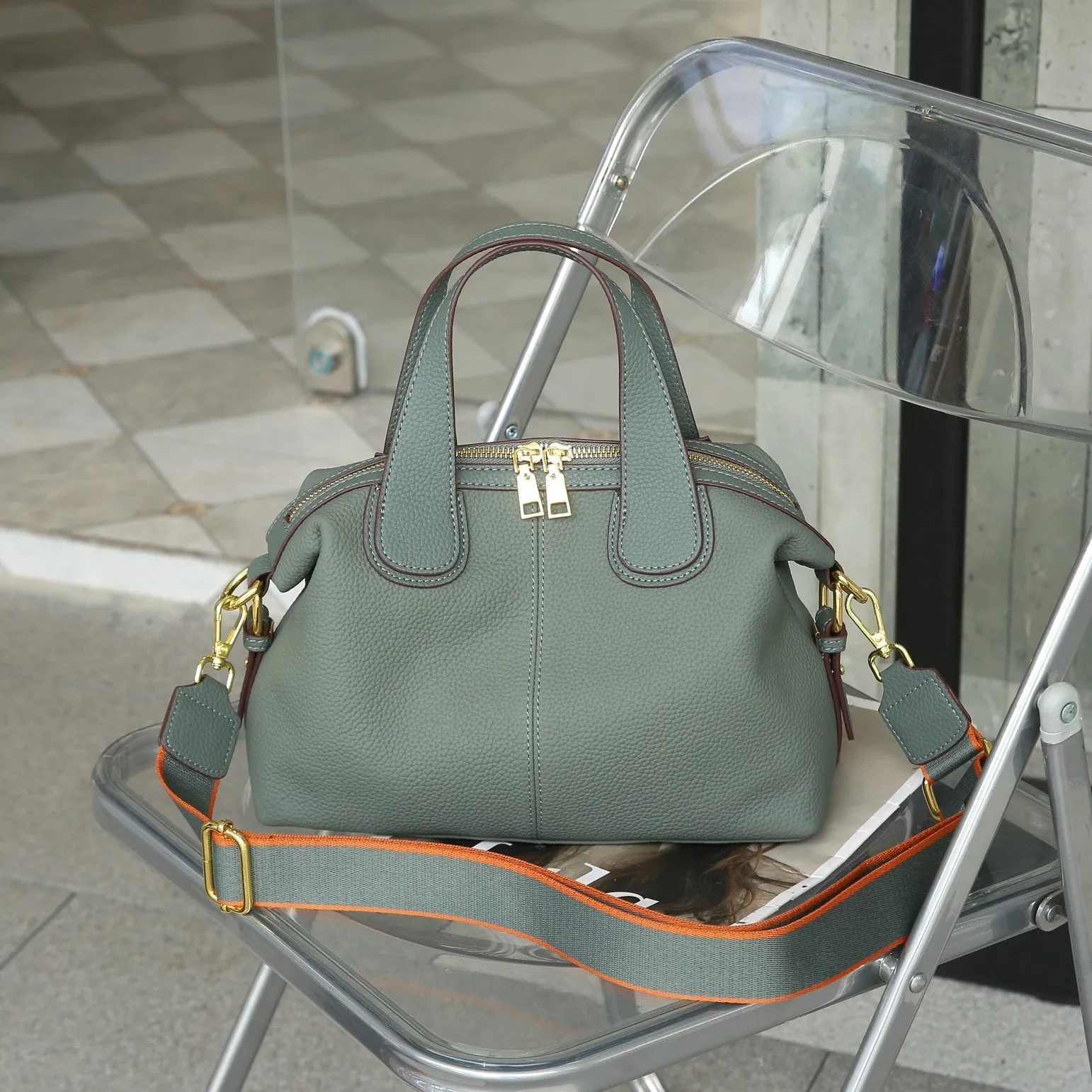 Women's leather cross-body bag in horizontal square shape with visible sewing thread detailing and interior compartments