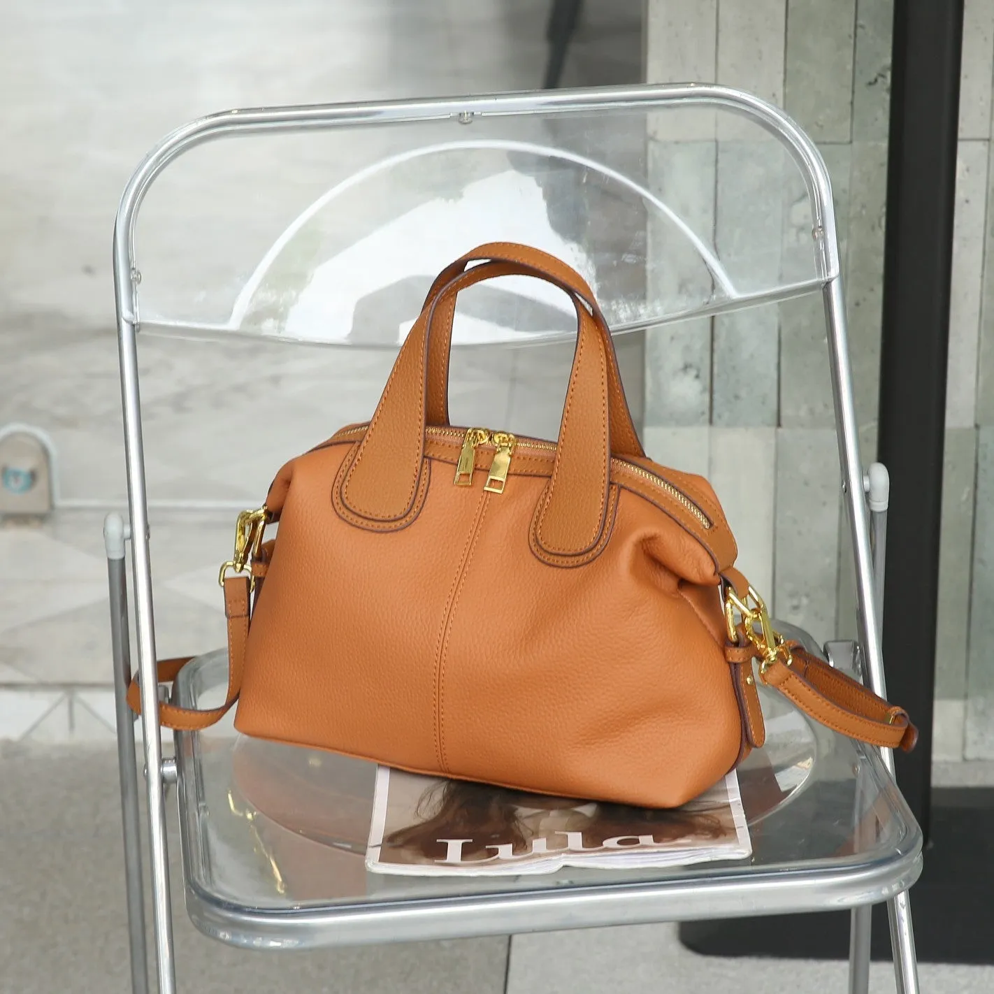 Women's leather cross-body bag in horizontal square shape with visible sewing thread detailing and interior compartments