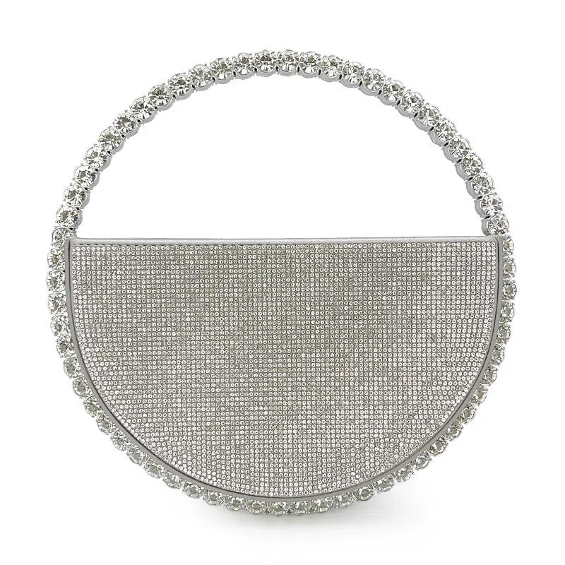 Round silver white PU evening bag with rhinestone details and crossbody strap on flat surface