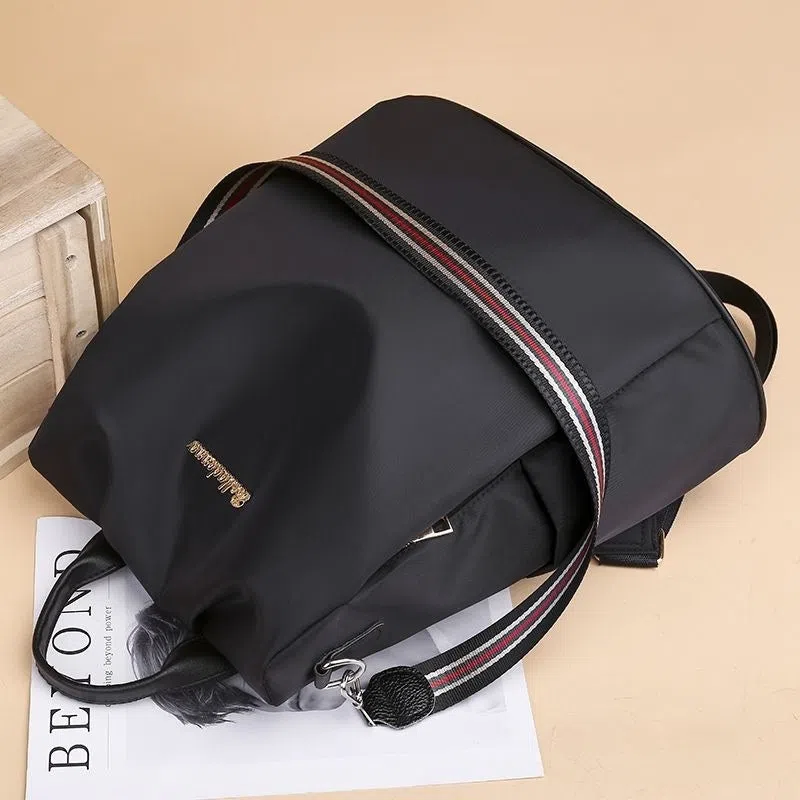 Women's large capacity black backpack with Oxford fabric lining, laptop sleeve, and trendy stitched seams and colour blocking