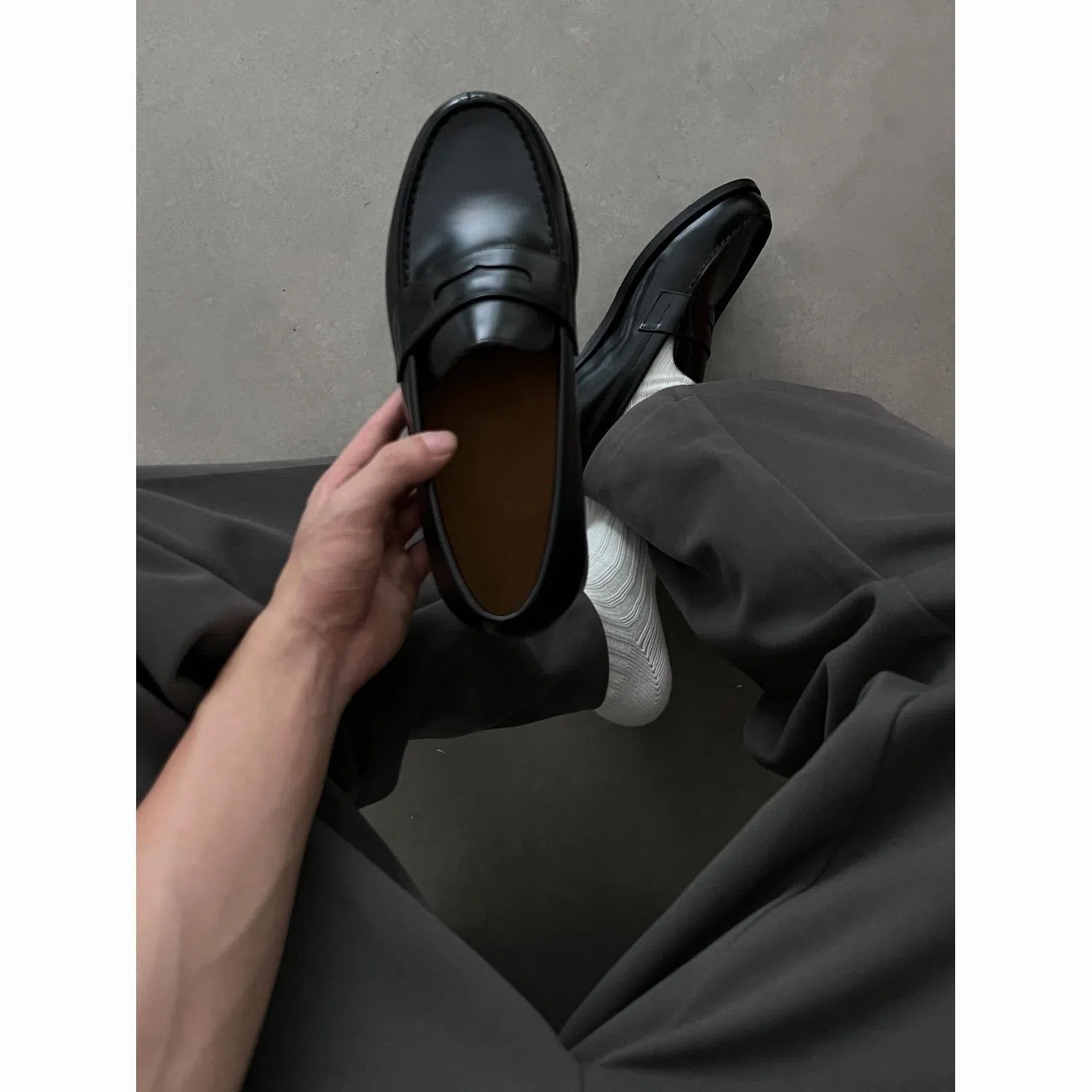 Men's black leather loafers with stitched seams, square heel, and vulcanised rubber sole on display
