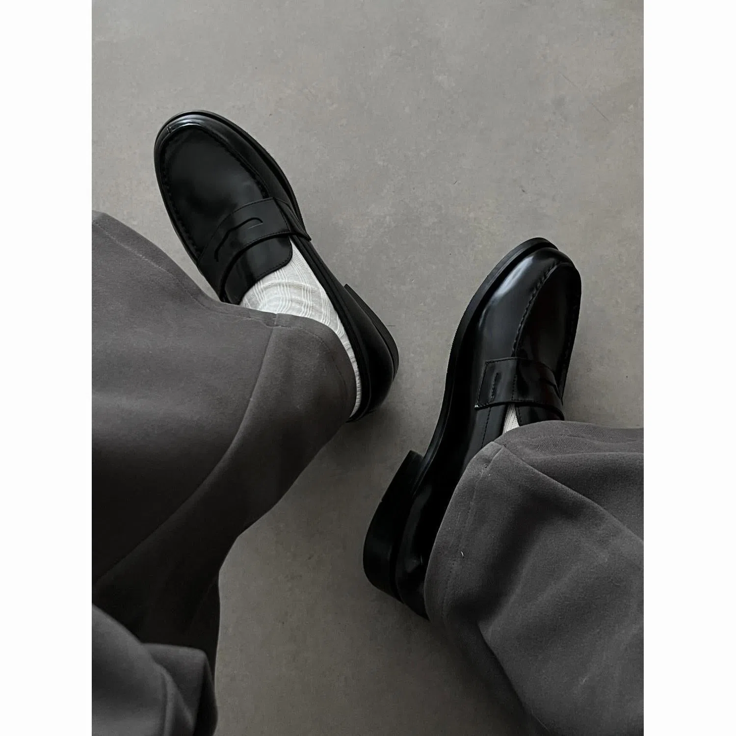 Men's black leather loafers with stitched seams, square heel, and vulcanised rubber sole on display