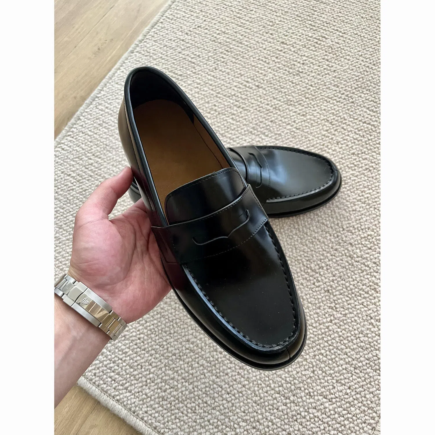 Men's black leather loafers with stitched seams, square heel, and vulcanised rubber sole on display