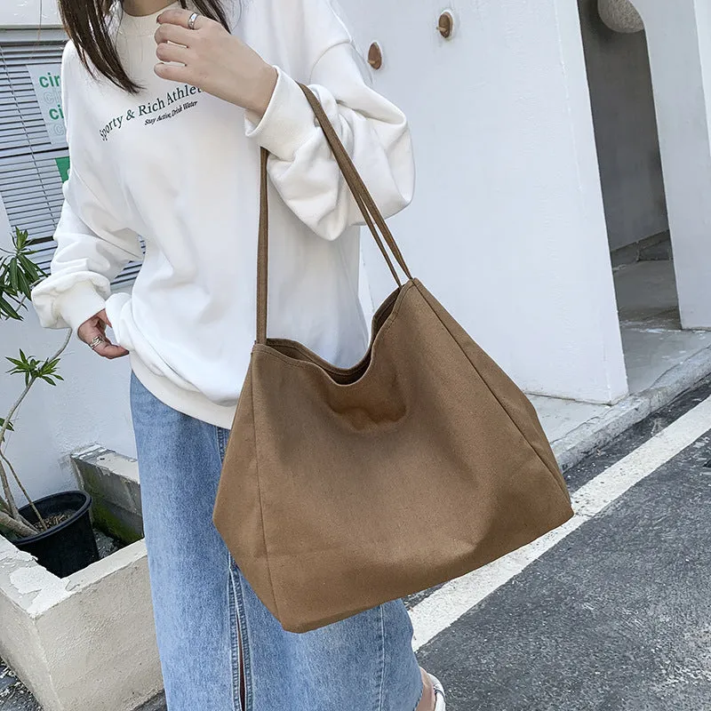 Women's black canvas shopping handbag with double shoulder straps showing internal mobile phone pocket