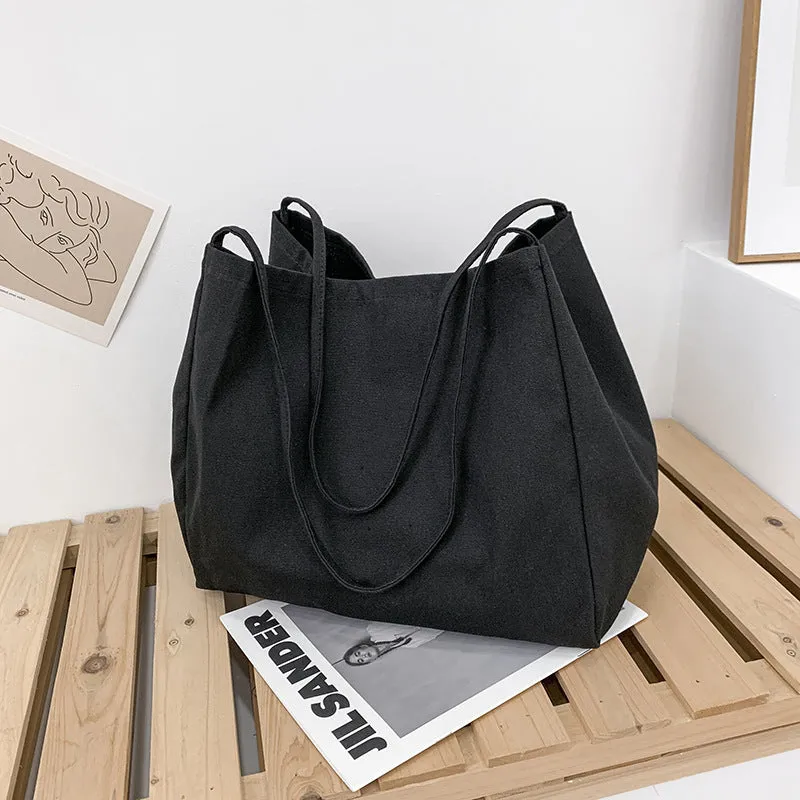 Women's black canvas shopping handbag with double shoulder straps showing internal mobile phone pocket